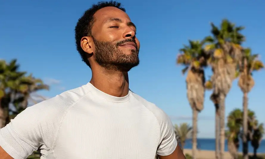 African American man breathing deeply in nature. Black man in sports clothing feeling good after exercising