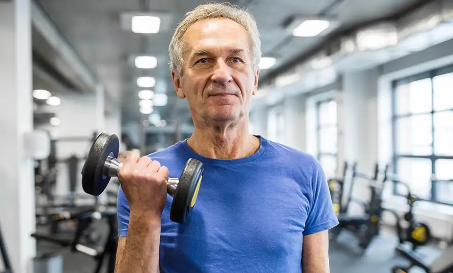 Strong senior man holding dumbbell in gym